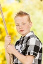 Young boy clutching a rope outdoors in the garden