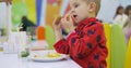 Young boy in a colorful diner, savoring a crispy chicken nugget