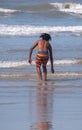 Young boy in colourful striped shorts plays in the waves at Port St Johns, Transkei, South Africa.