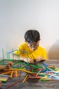 A young boy is constructing colorful plastic sticks with glue gun. fun with building geometric figures and learning mathematics at Royalty Free Stock Photo