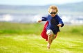 Young boy, costume and running in park, playing and carefree outdoor with happiness or playful child on grass. Freedom