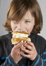 Young boy with a cream bun with almond paste Royalty Free Stock Photo