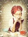 Young boy cute cook chef in red uniform and hat on stained face with glasses sitting on table with colorful bowls, tasty