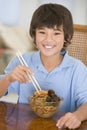 Young boy in dining room eating chinese food Royalty Free Stock Photo