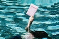 A young boy diving and taking out of the swimming pool a pink passport. Creative concept for hotel resort or travel agency Royalty Free Stock Photo