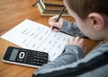 Young boy doing maths homework test times tables multiplication exam paper sat at table homeschooling education with calculator Royalty Free Stock Photo