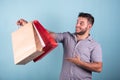 young boy doing shopping with paper bags blue background