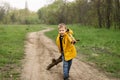 A young boy drags a tree branch along a dirt road in the forest