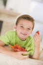 Young boy eating bowl of vegetables in living room Royalty Free Stock Photo