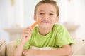 Young boy eating carrot stick in living room Royalty Free Stock Photo