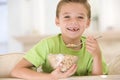 Young boy eating cereal in living room smiling Royalty Free Stock Photo