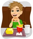 Young boy eating cheeseburger with french fries and coke