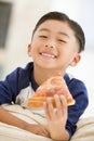 Young boy eating pizza slice in living room Royalty Free Stock Photo