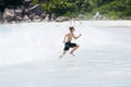 Young boy enjoys the summer holiday at beach, escaping from big splashing wave.