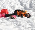 Young boy falls from red sleigh in the mountains Royalty Free Stock Photo