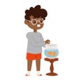 Young boy feeding goldfish in a bowl, smiling African-American child caring for pet. Cheerful kid enjoys fishkeeping