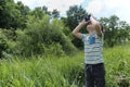 Young boy in a field looking through binoculars.