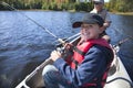 A young boy fisherman smiles as he reels in a fish