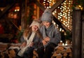 Young boy and girl sitting on logs before home terrace with Christmas background Royalty Free Stock Photo