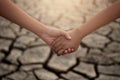 Young boy and girl holding hands on cracks in the dried soil in arid season. Saving environment and natural conservation concept Royalty Free Stock Photo