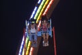 Young boy and girl riding high speed amusement ride laughing and crying with fear, deep night