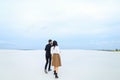 Young boy and girl walking on snow in monophonic background.