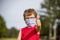 Young boy gives thumbs up while wearing mask