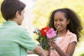 Young boy giving young girl flowers and smiling Royalty Free Stock Photo