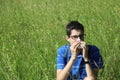 Young boy with glasses blowing his nose because of allergy in th Royalty Free Stock Photo