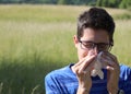 Young boy with glasses blowing his nose because of allergy in th Royalty Free Stock Photo