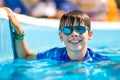 Young boy in googles holding edge of swimming pool. Enjoying time in the refreshing water Royalty Free Stock Photo