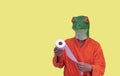 Young boy with a green frog animal mask in an orange bathrobe with a white toilet paper roll on a yellow background with copy Royalty Free Stock Photo