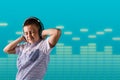 Young boy happily dancing listening to music on headphones  with a blue background and copy space  for text Royalty Free Stock Photo