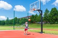 Young boy having fun playing basketball outdoors.nice,cool caucasian alone player playing basketball outdoors