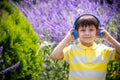 Young boy in headphones listening to modern music in nature. Child likes the song. Kid music relax concept after school classes