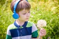 Young boy in headphones listening to modern music in nature. Child likes the song and look to giant dandelion. Kid music relax