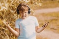 Young boy in headphones with smartphone listens to music in the park Royalty Free Stock Photo