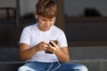 Young boy in headphones with smartphone listens to music in the park Royalty Free Stock Photo