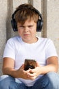 Young boy in headphones with smartphone listens to music in the park Royalty Free Stock Photo