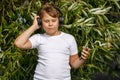 Young boy in headphones with smartphone listens to music in the park Royalty Free Stock Photo