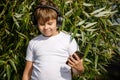 Young boy in headphones with smartphone listens to music in the park Royalty Free Stock Photo