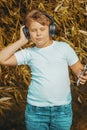 Young boy in headphones with smartphone listens to music in the park Royalty Free Stock Photo