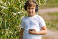 Young boy in headphones with smartphone listens to music in the park Royalty Free Stock Photo