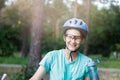 Young boy in helmet and green t shirt cyclist drinks water from bottle in the park. Smiling cute Boy on bicycle in the forest Royalty Free Stock Photo