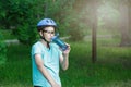 Young boy in helmet and green t shirt cyclist drinks water from bottle in the park. Smiling cute Boy on bicycle in the forest Royalty Free Stock Photo