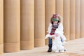 Young boy and his baby sister on a walk next to a modern building entrance with pillars