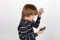 Young boy holding a basic mobile phone and not too happy with it Royalty Free Stock Photo