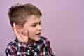 Young boy holding his hand on the ear-eavesdropping