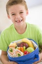 Young boy holding packed lunch in living room Royalty Free Stock Photo