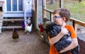 Young boy holding pet rooster in coop Royalty Free Stock Photo